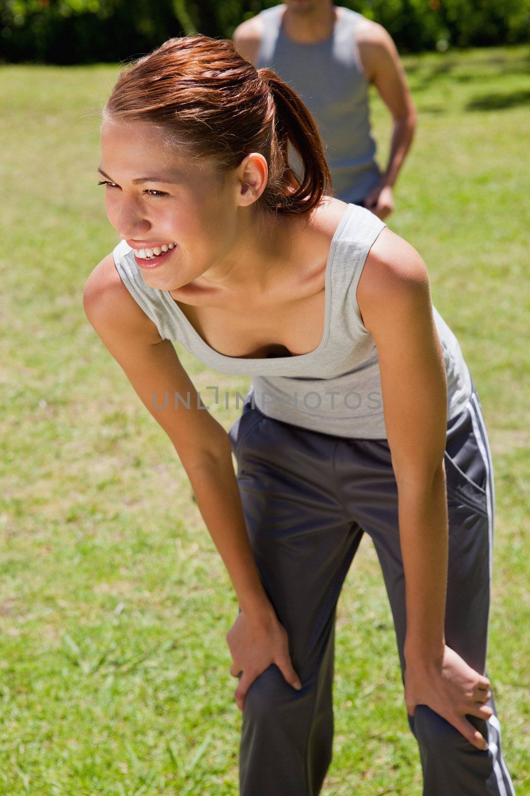 Woman smiling while bending over to recover as a man is walking close behind her