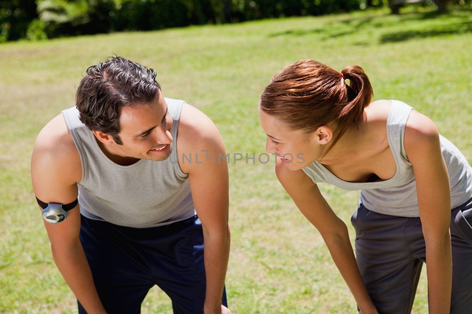 Man and a woman bending over as they recover while looking at each other