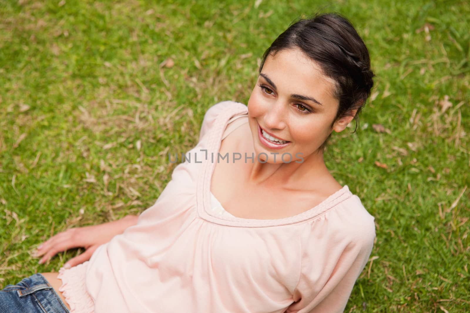 Woman smiling and looking straight ahead as she lies down on the grass