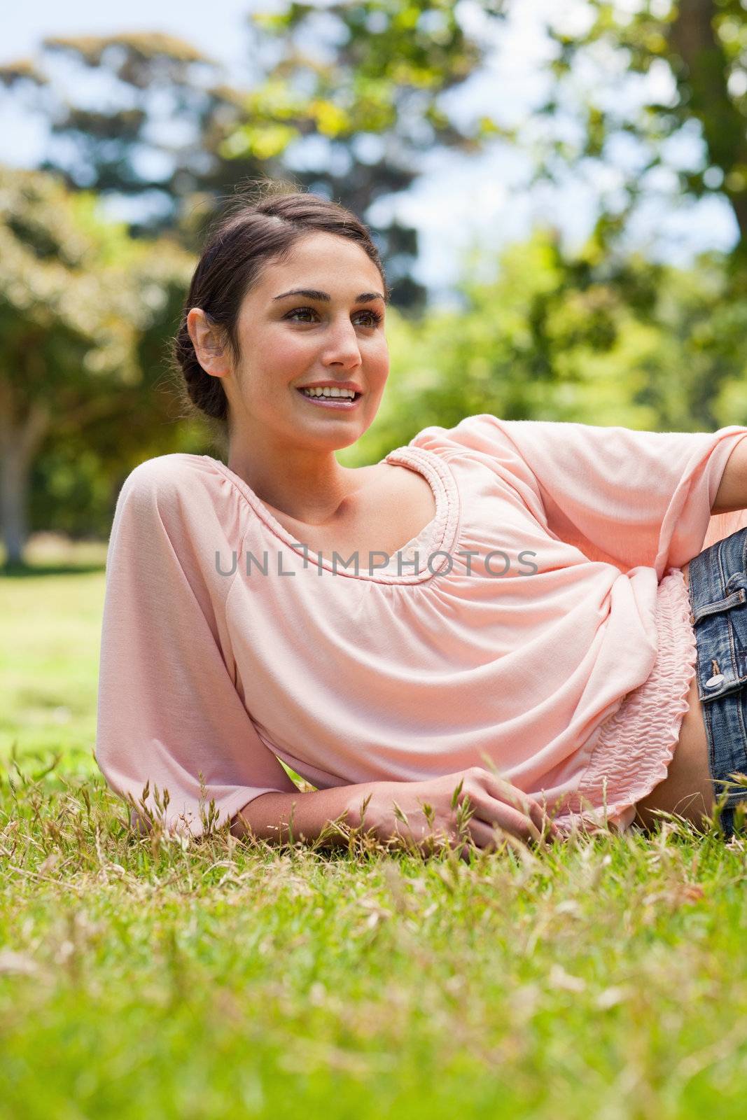 Smiling woman looking to her left while lying on her side by Wavebreakmedia