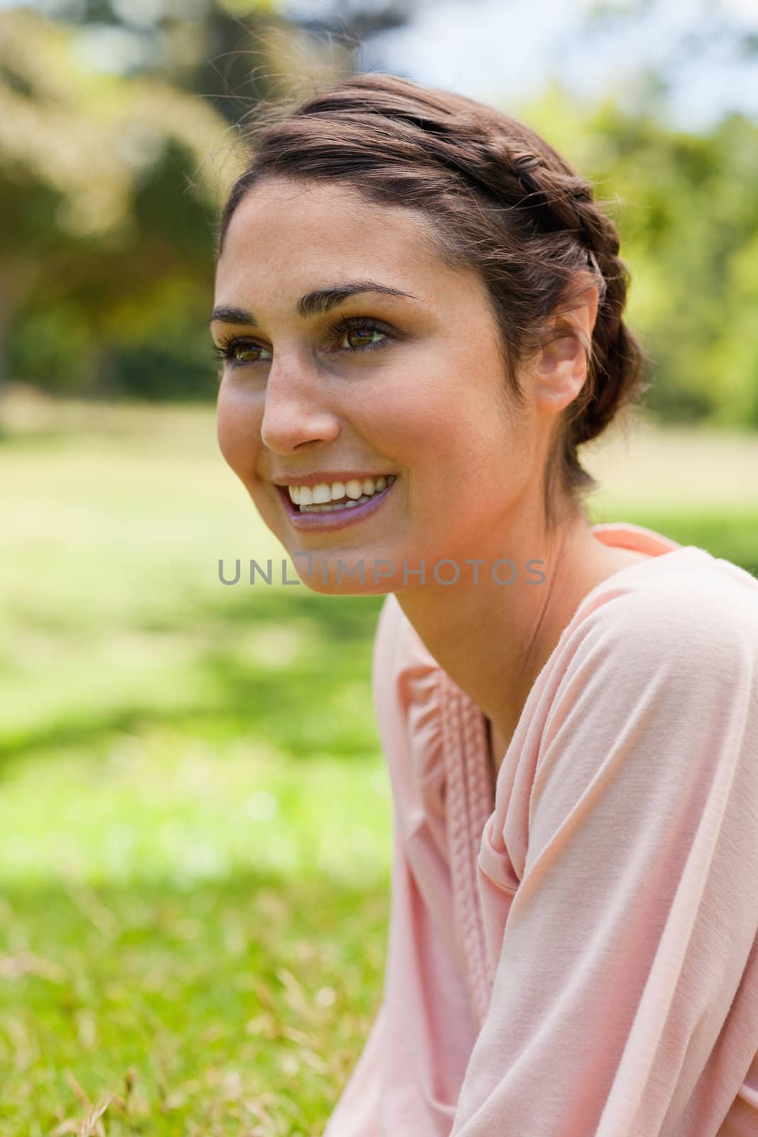 Woman looking into the distance while sitting on the grass by Wavebreakmedia