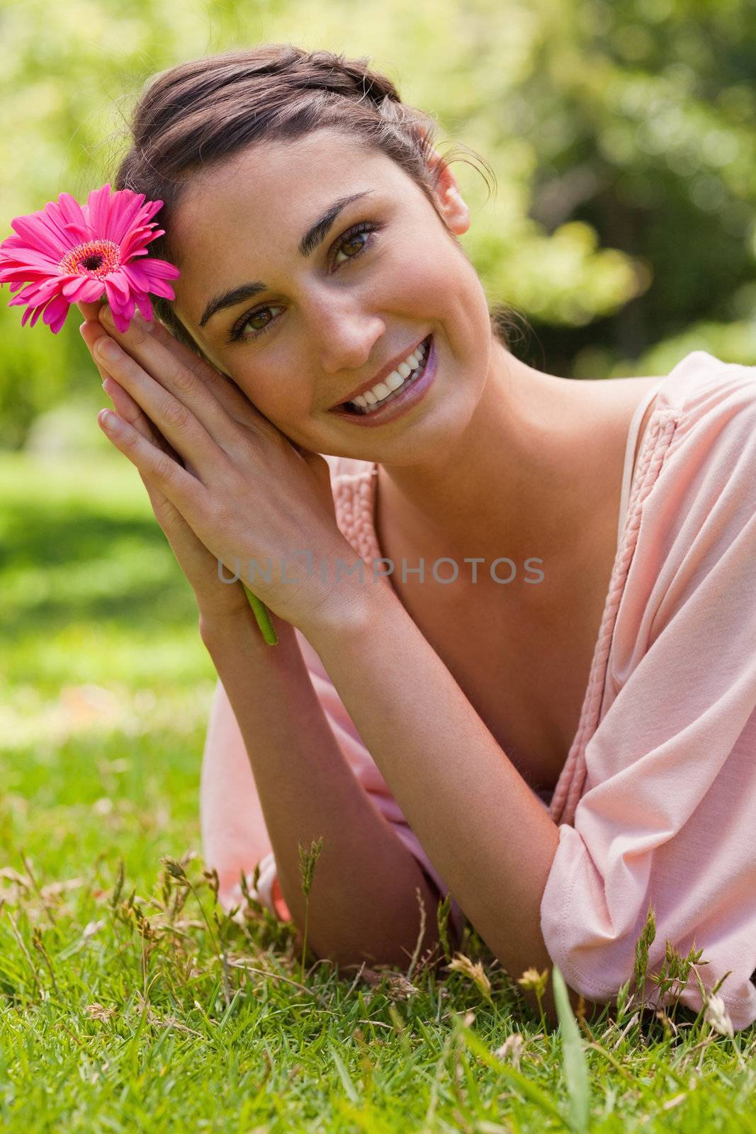 Woman restling her head against her arms while holding a flower by Wavebreakmedia