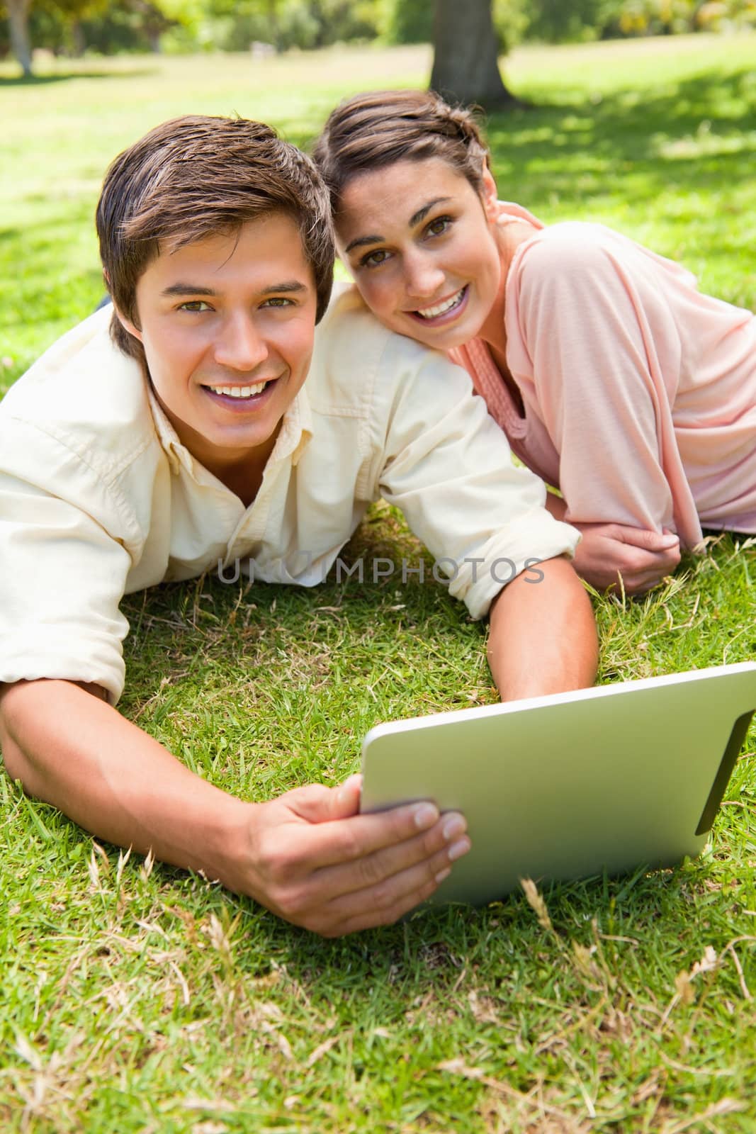 Two friends looking ahead as they use a tablet together by Wavebreakmedia