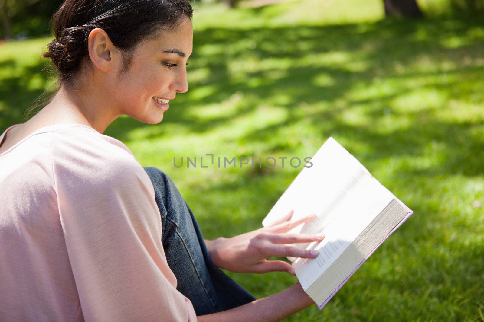 Woman reading a book while sitting in the grass by Wavebreakmedia