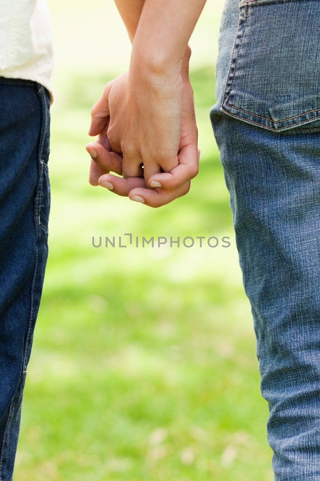 Man and a woman holding hands while standing in grass