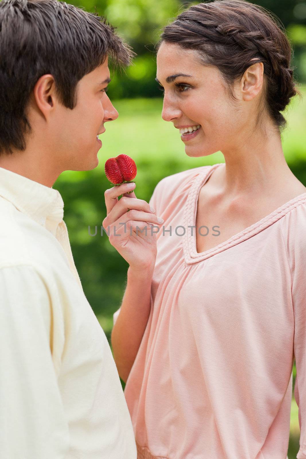 Woman laughing while offering a strawberry to her friend by Wavebreakmedia