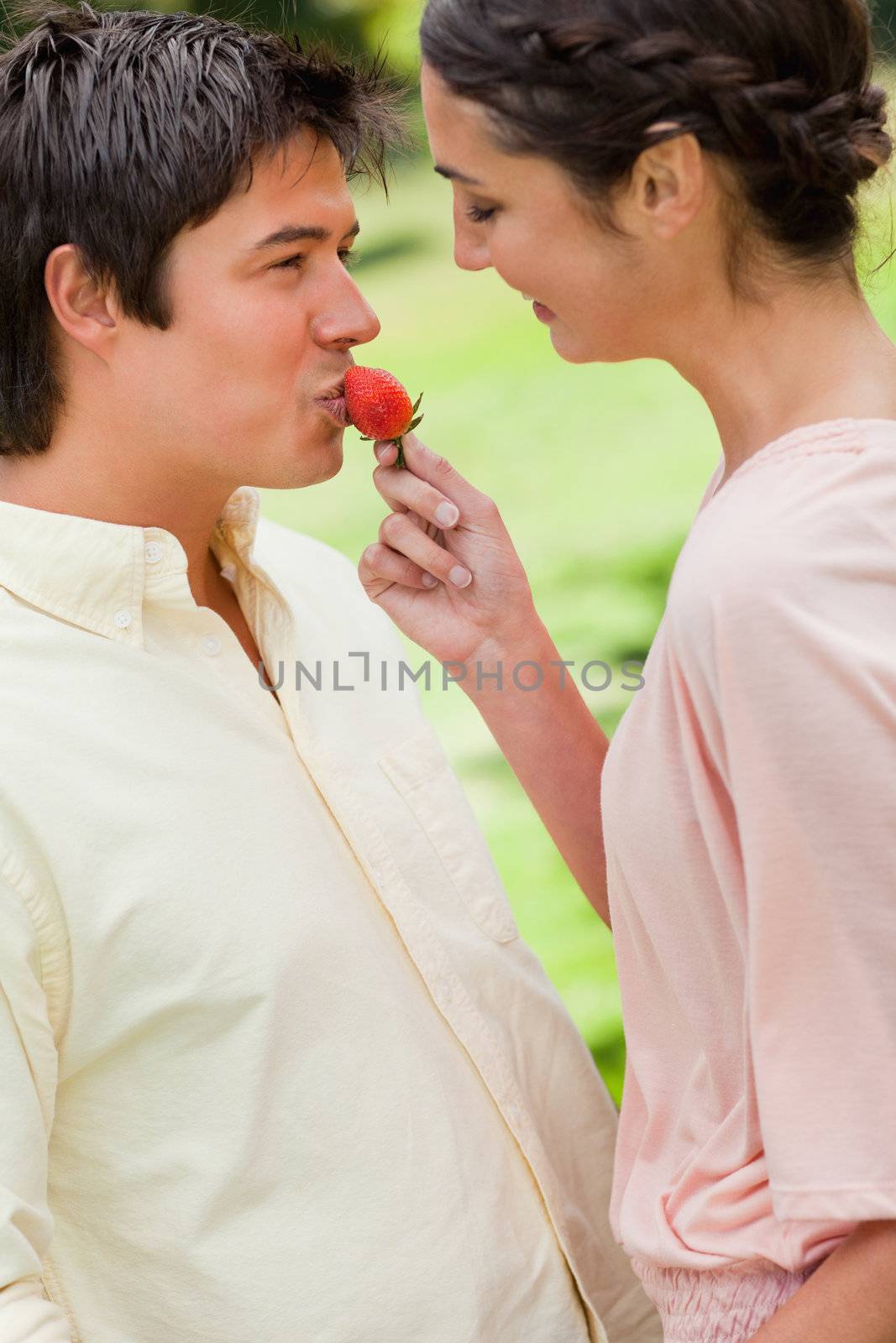 Woman smiles as she feeds her friend a strawberry in a park