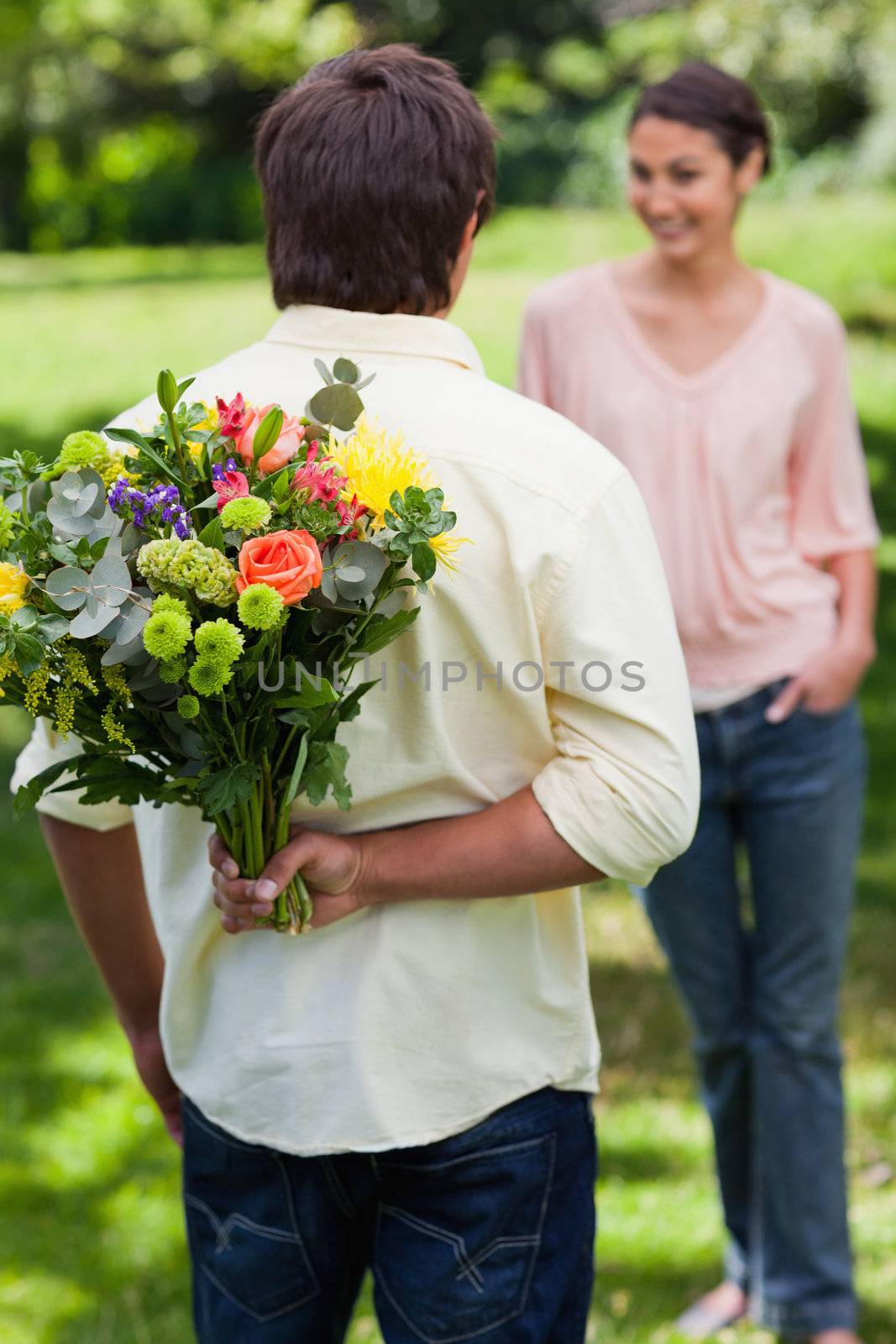 Man about to surprise his friend with a bouquet of flowers by Wavebreakmedia