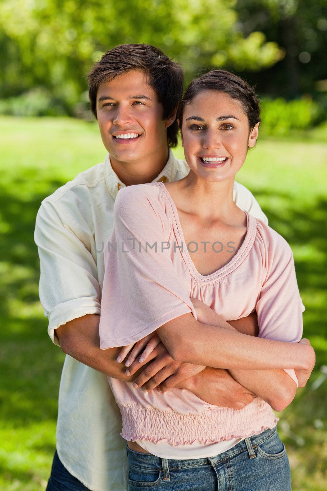 Man and woman looking straight ahead of them while he is holding onto her waist
