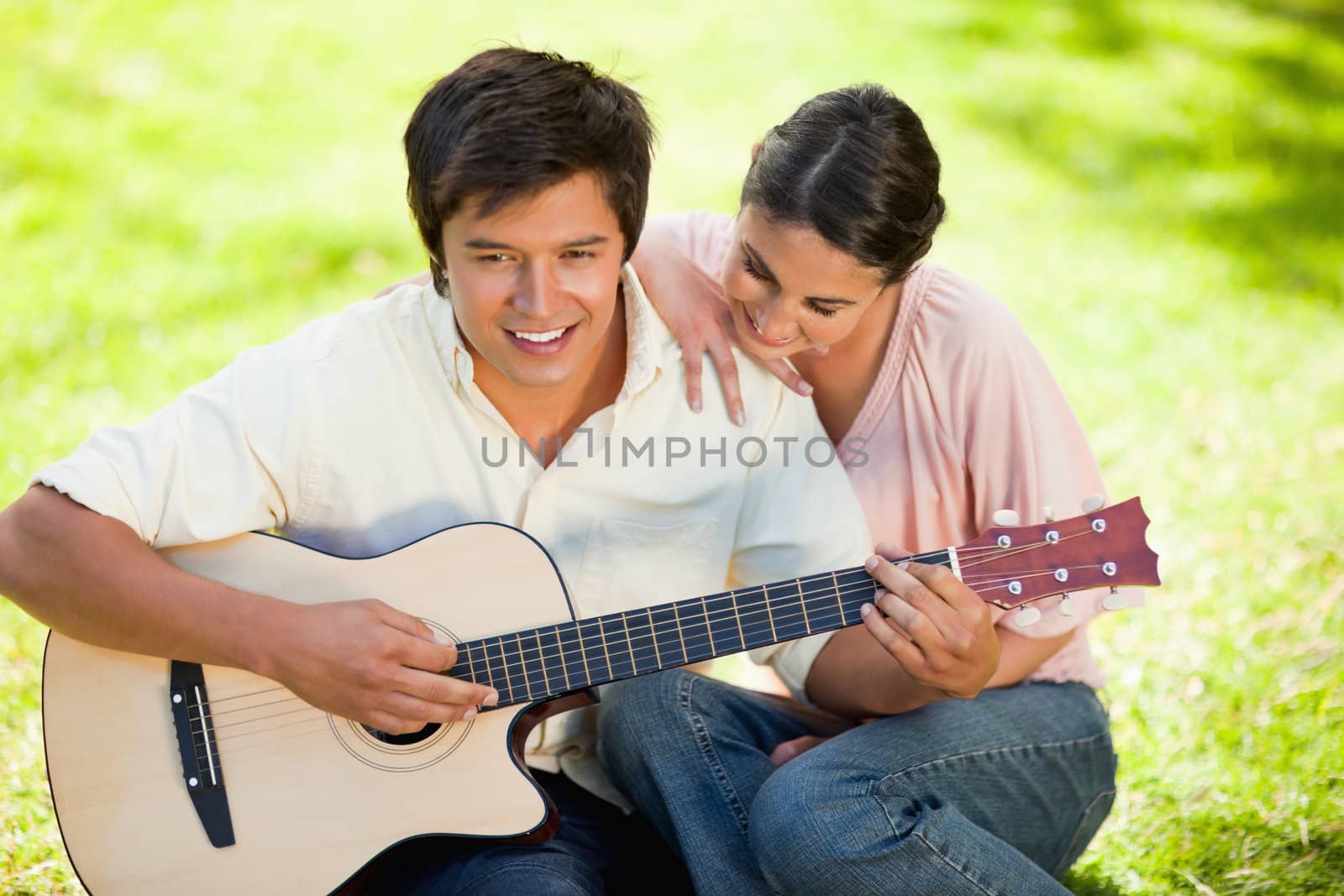 Woman leaning while leaning on her friends shoulder as he plays  by Wavebreakmedia