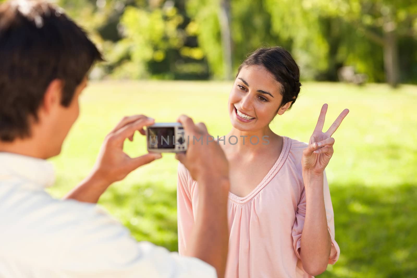 Man takes a photo of his friend giving the peace sign by Wavebreakmedia