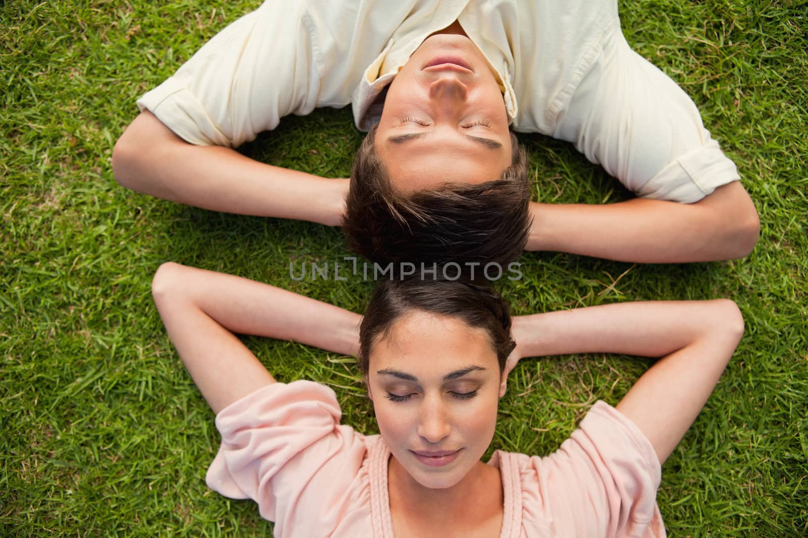 Close-up of two friends lying head to head with both hands behin by Wavebreakmedia