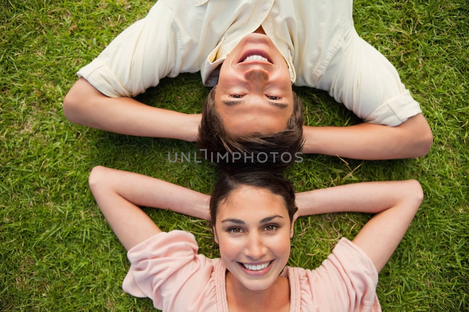 Two friends smiling while lying head to head with both hands beh by Wavebreakmedia