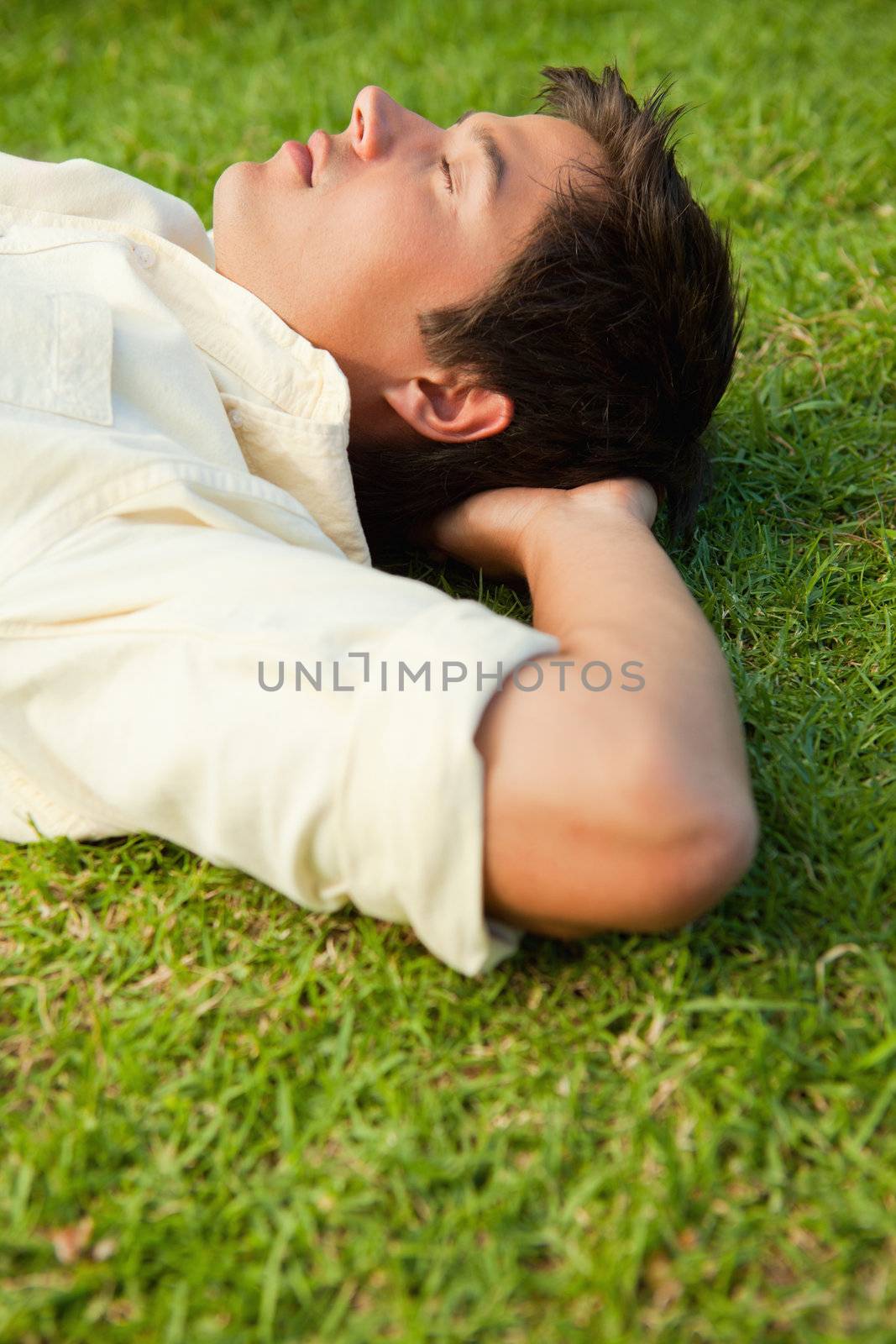 Side view of a man lying with his eyes closed and his head resti by Wavebreakmedia