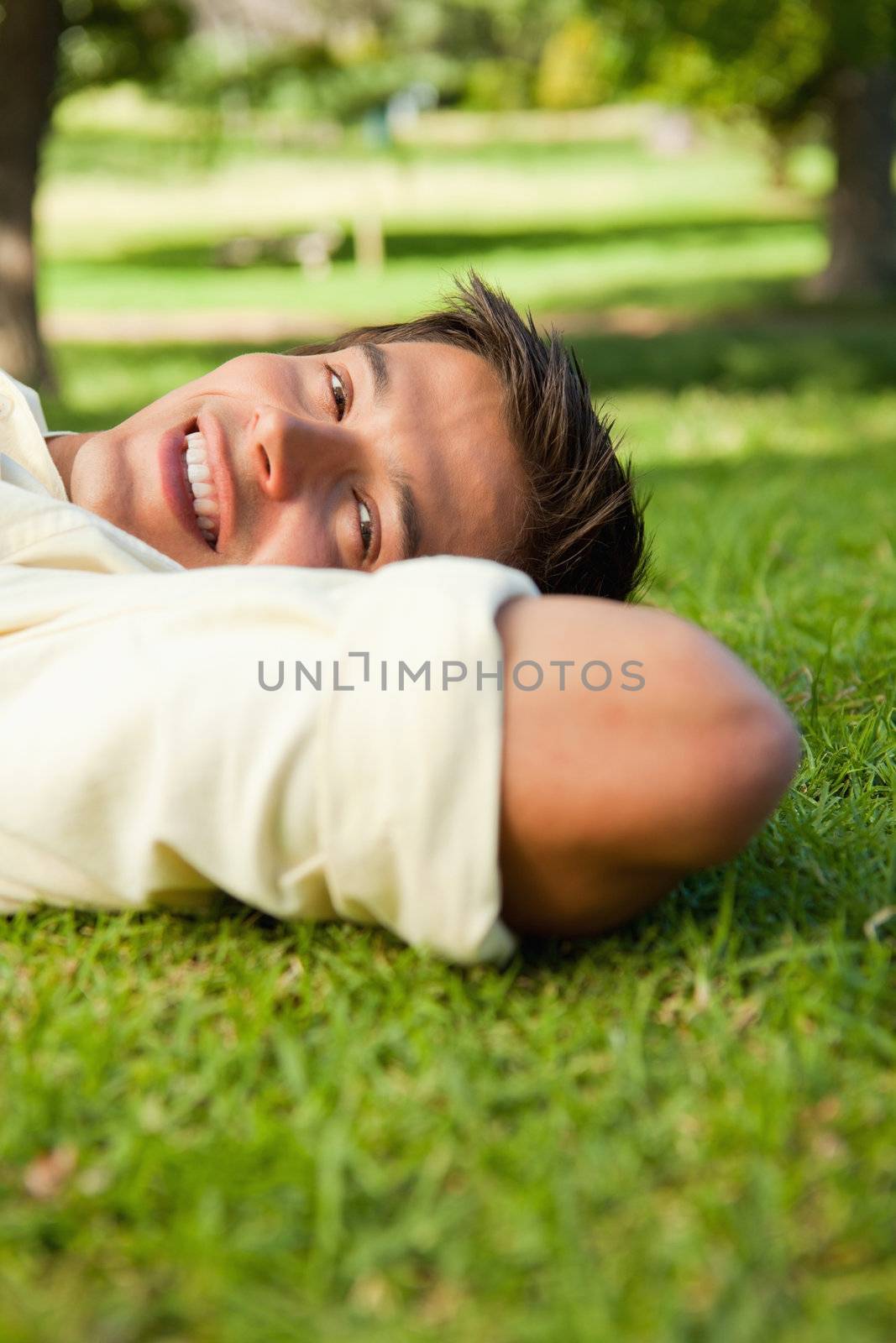 Man smiling while lying with the side of his head resting on his by Wavebreakmedia