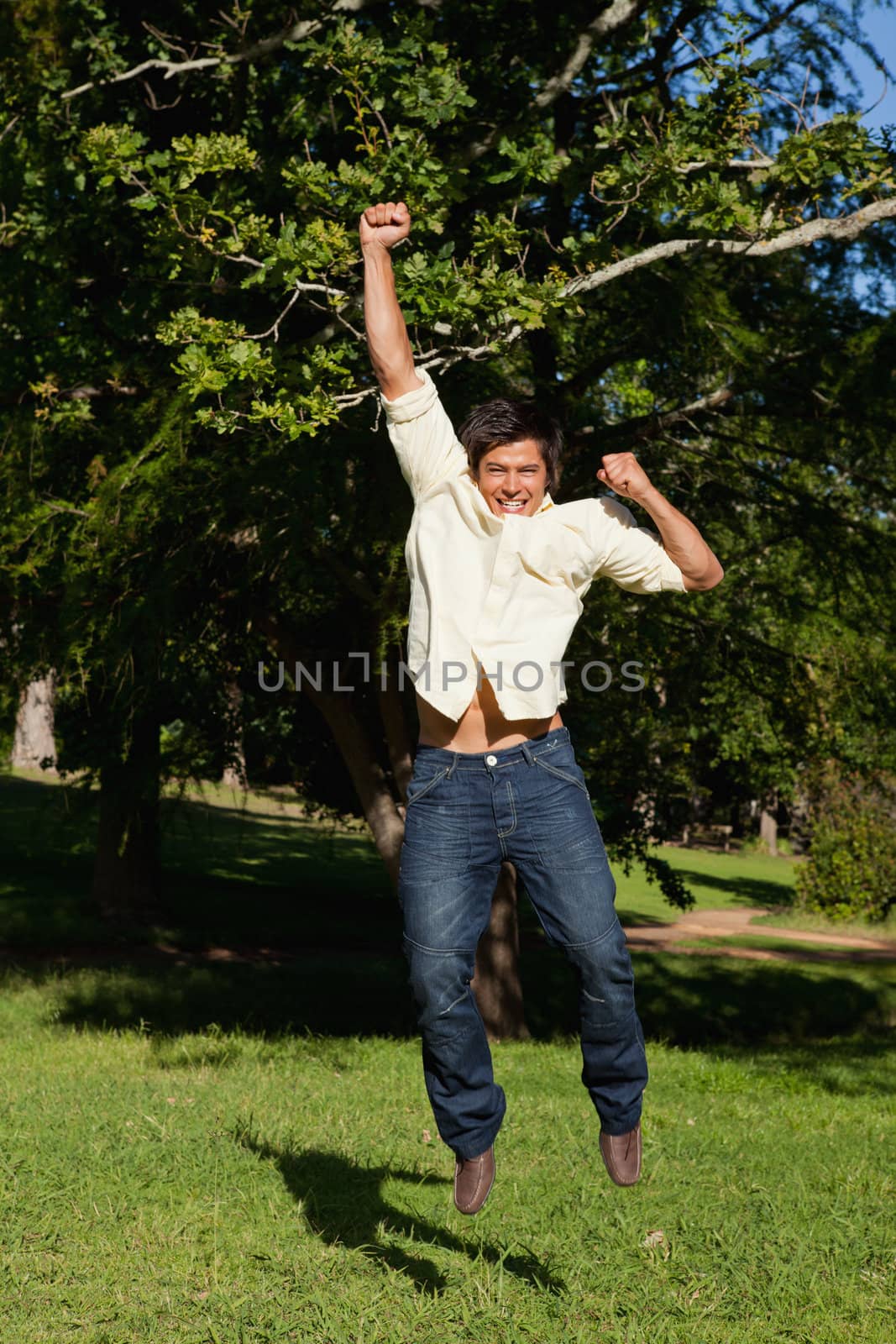 Man jumping with his arms raised as he rejoices by Wavebreakmedia