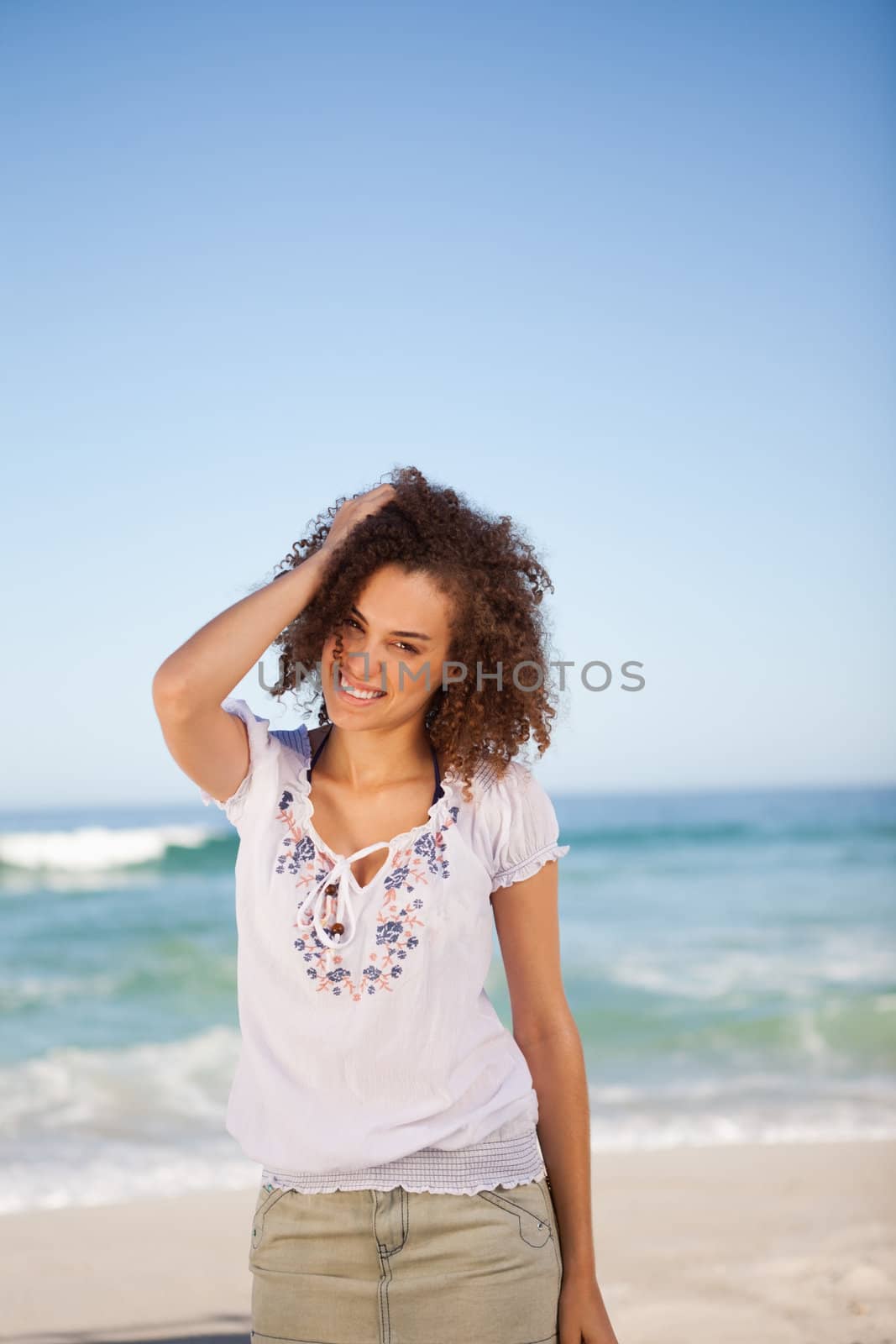 Young woman standing in front of the sea with hand on her head by Wavebreakmedia