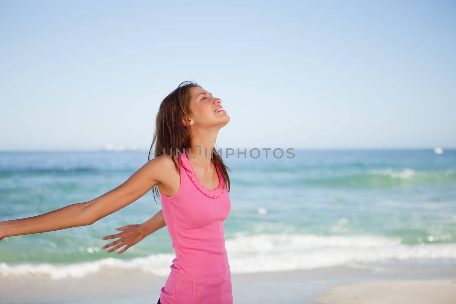 Young woman standing with arms back while sunbathing on the beach
