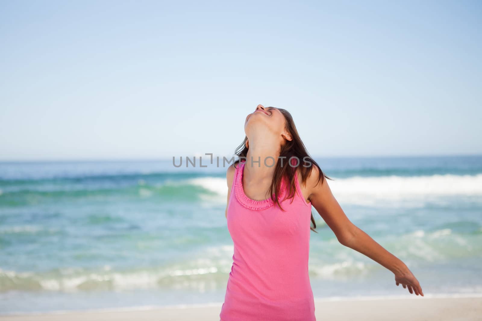 Young relaxed woman standing in front of the sea while sunbathing