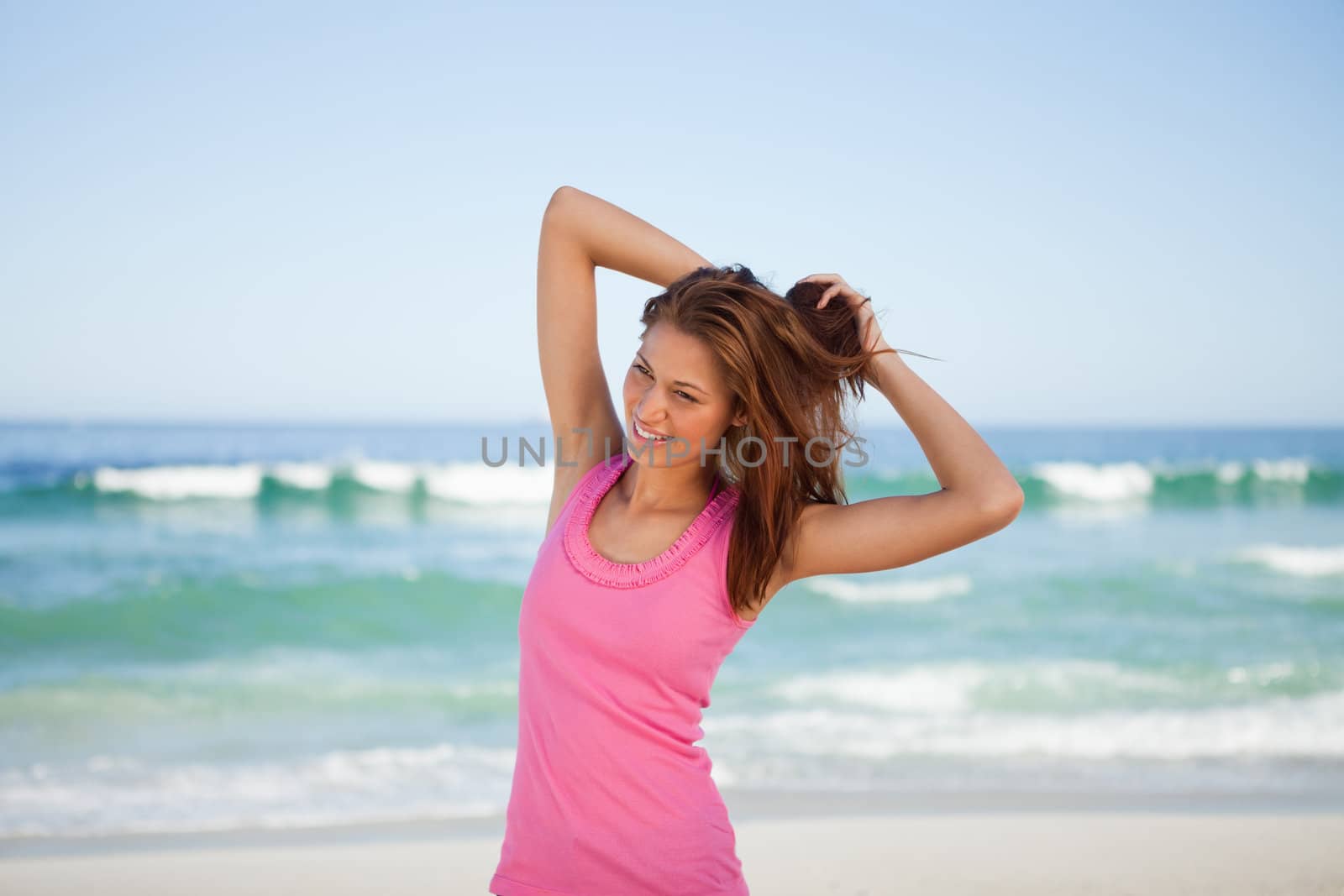 Young woman going to tie up her hair while standing in front of the sea