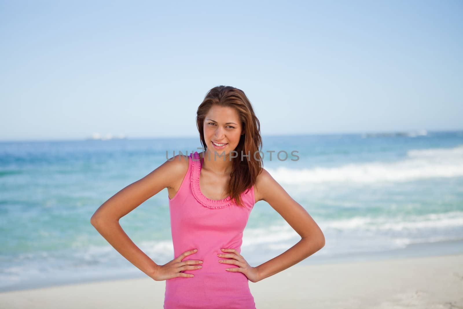 Young woman sunbathing while standing on the beach with hands on hips