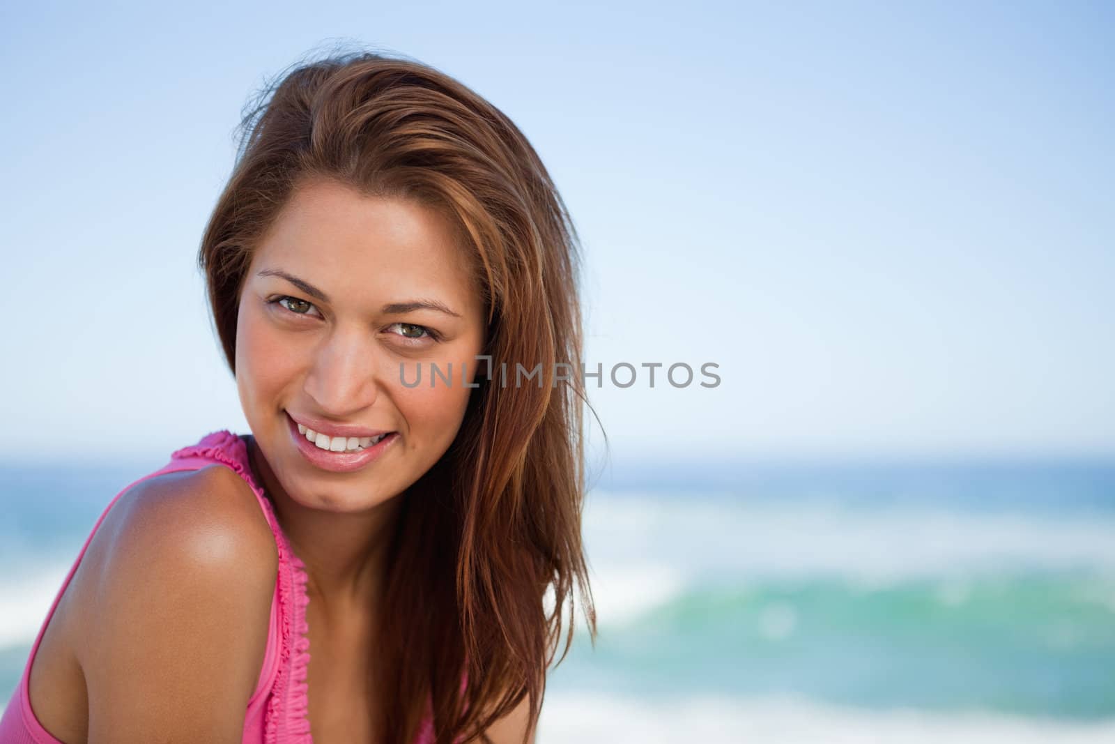Young woman staring at the camera while sunbathing on the beach