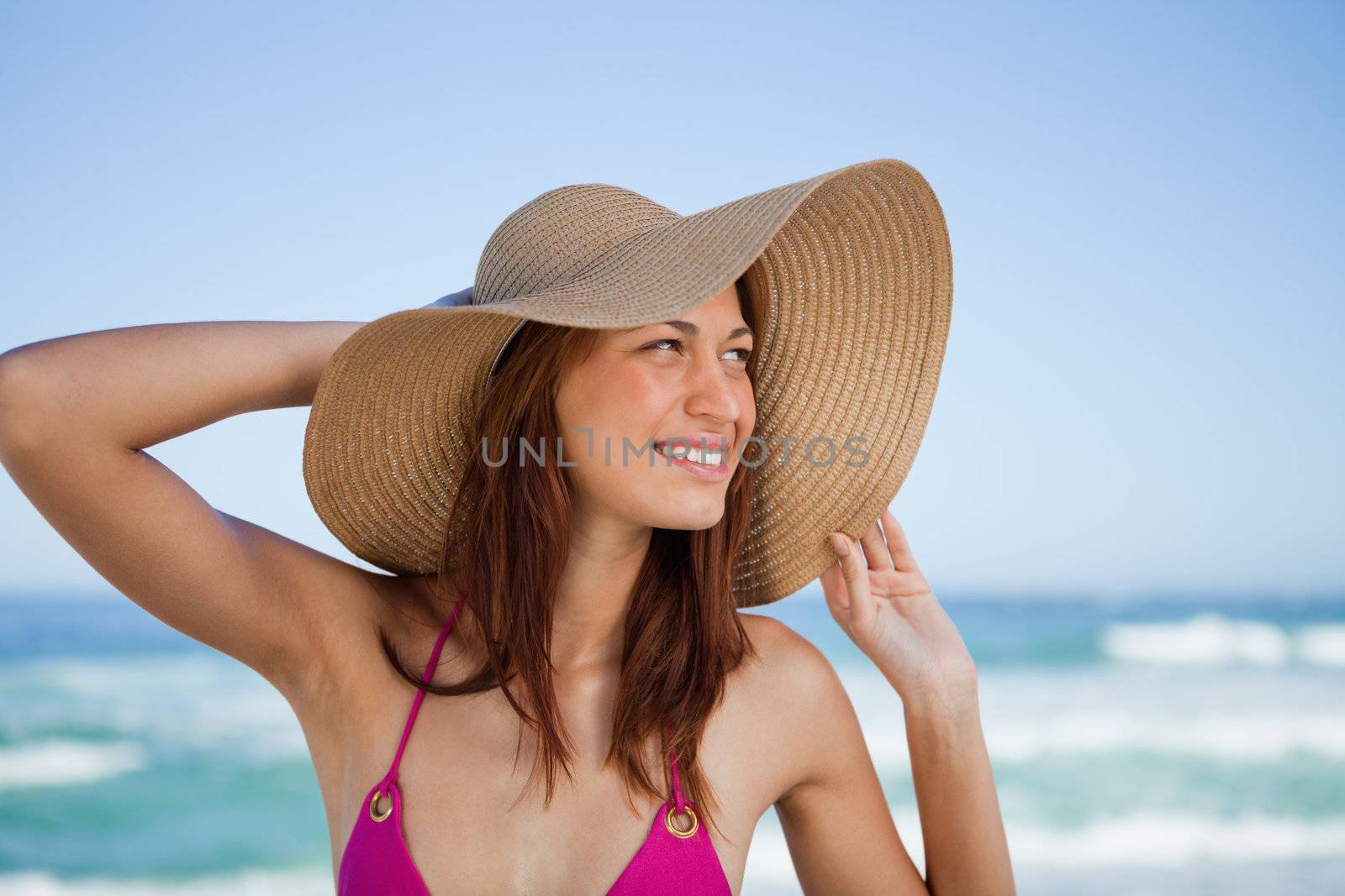 Smiling teenager standing on the beach while looking on the side