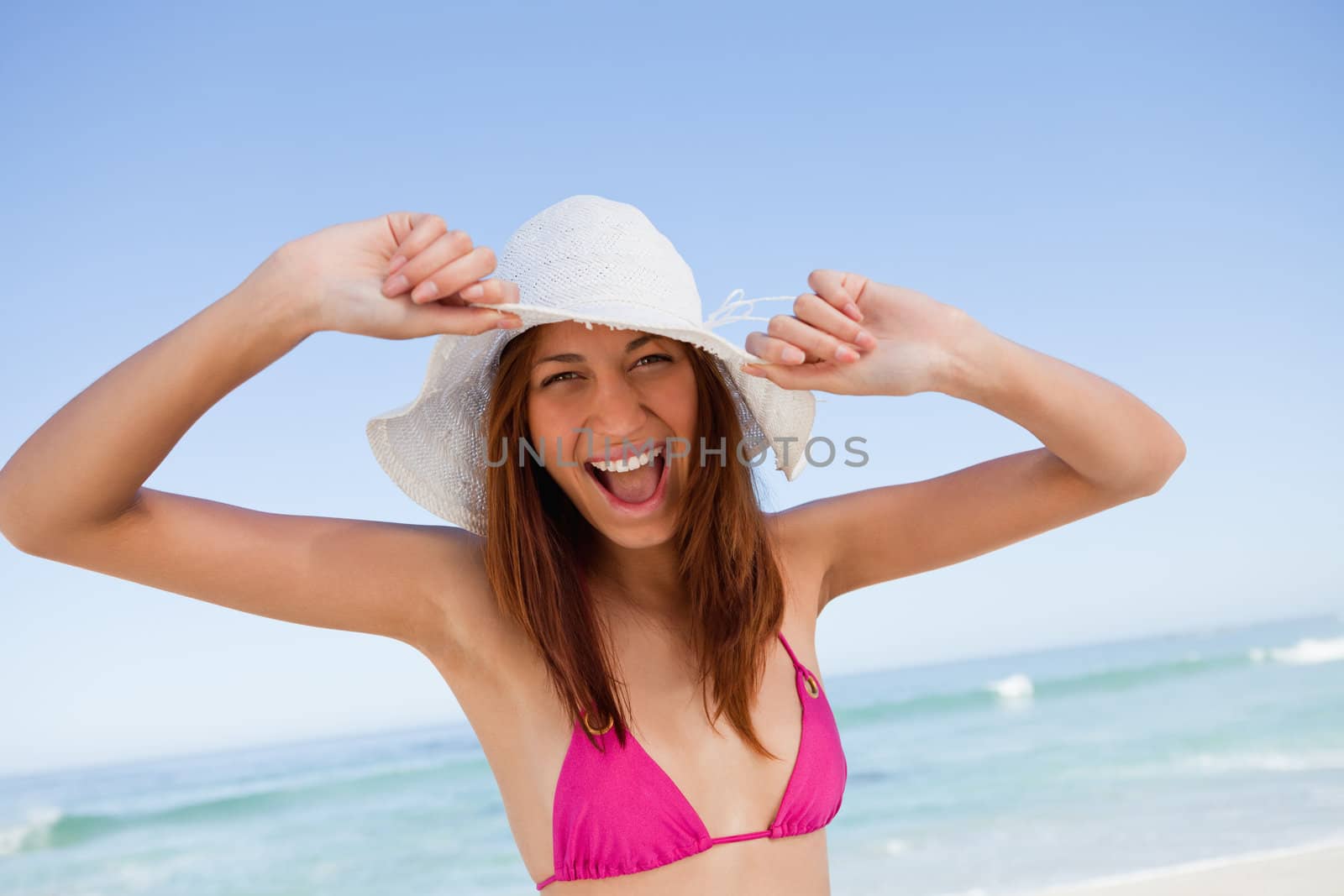 Young woman raising her arms in happiness in front of the sea by Wavebreakmedia