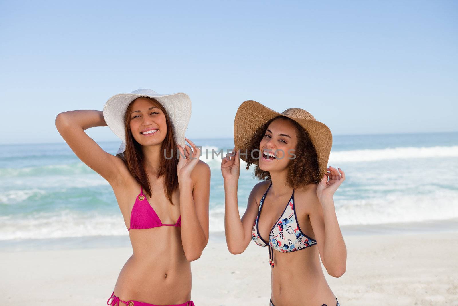 Happy young women standing on the beach side by side by Wavebreakmedia