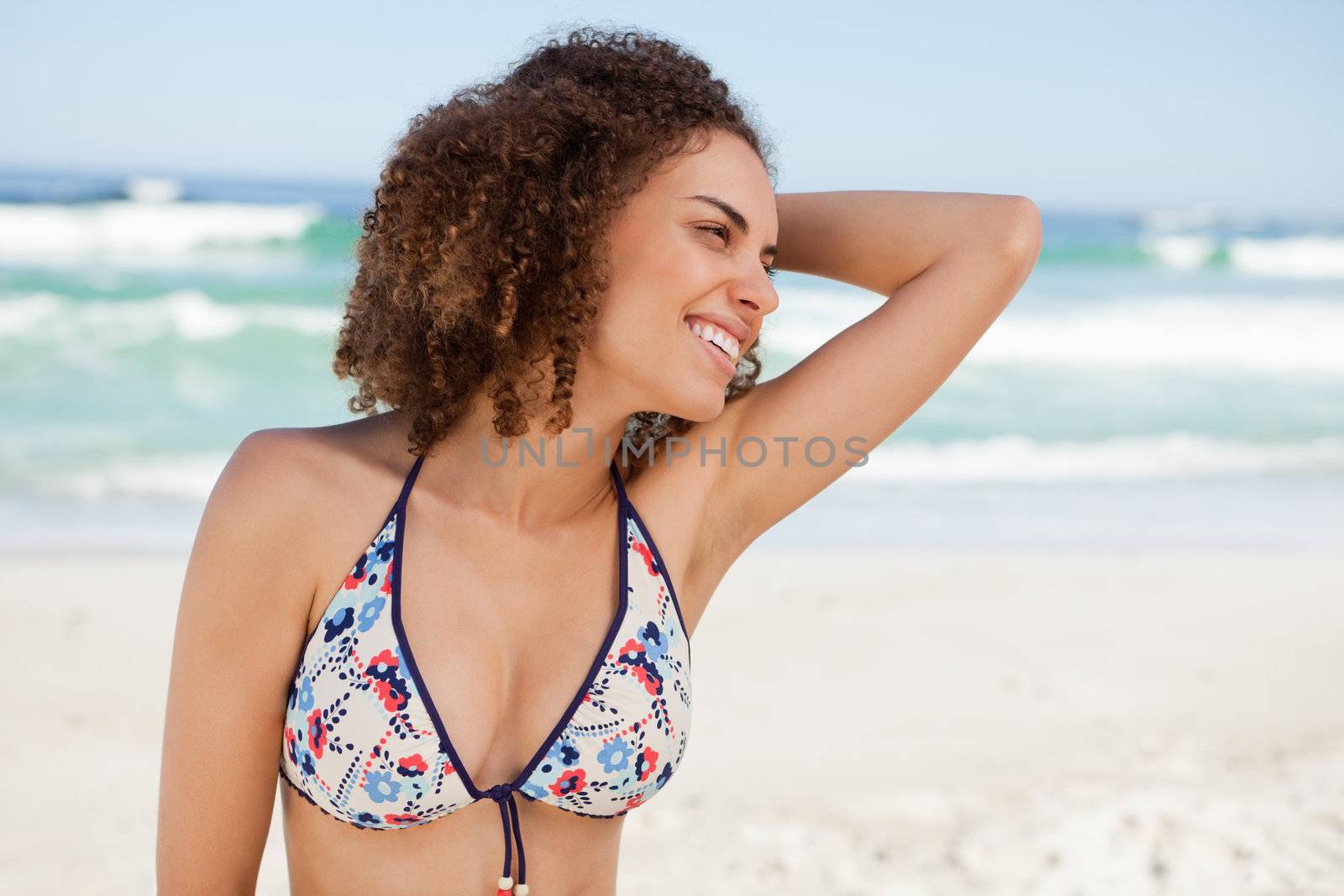 Young woman placing her hand on her hair while wearing a swimsuit on the beach