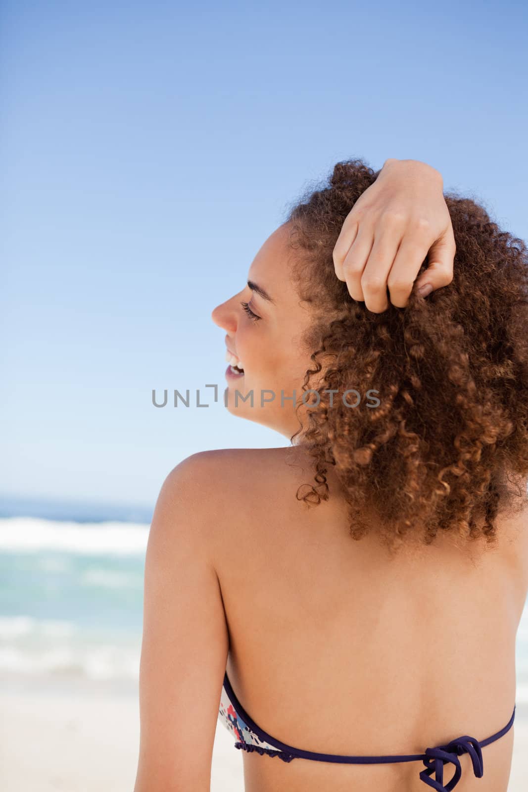 Back view of an attractive woman placing her hand on her hair in front of the sea