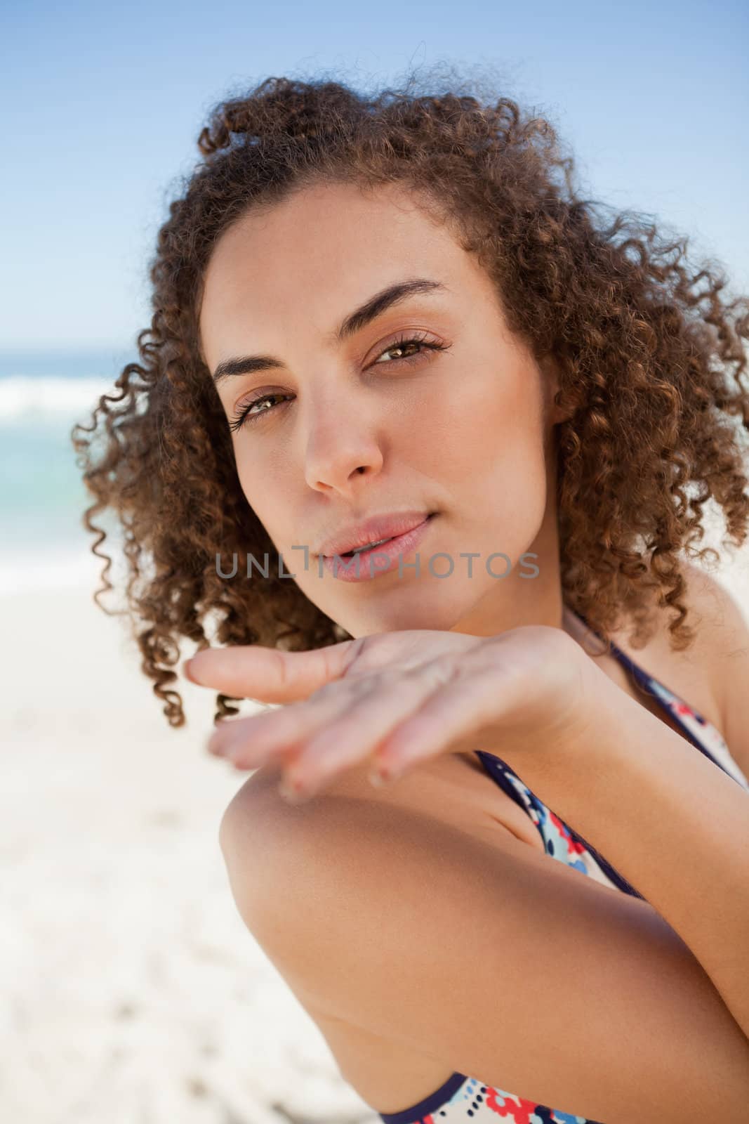 Young woman sending an air kiss while blowing on her hand by Wavebreakmedia