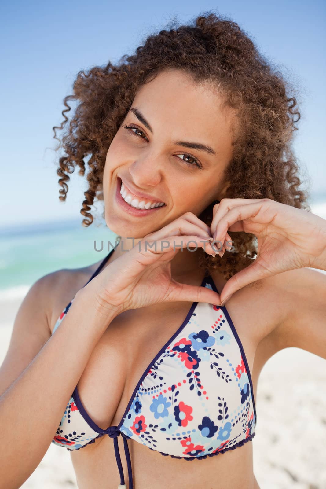 Smiling young woman making a heart with her hands by Wavebreakmedia