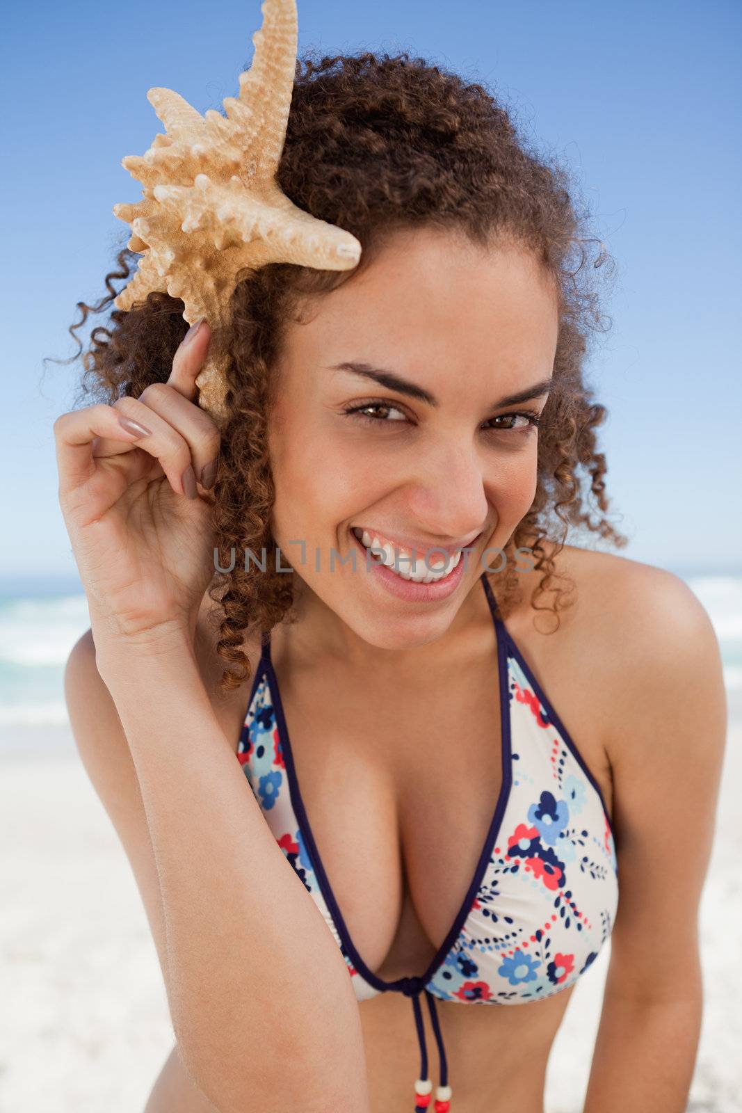 Young woman leaning her head forward while holding a starfish by Wavebreakmedia
