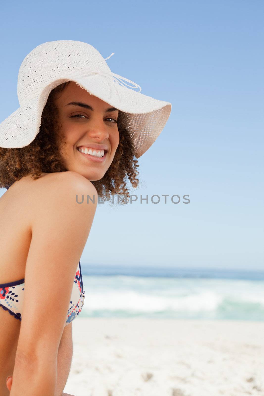 Smiling young wearing a straw hat and posing in front of the camera on the beach