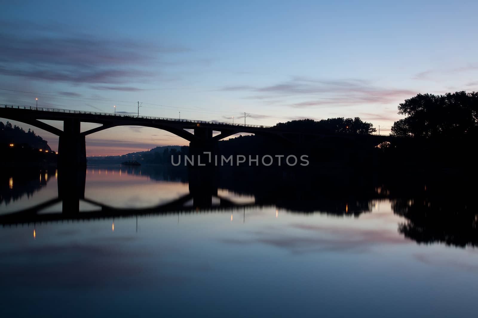 Railway bridge connecting river banks with reflection at sunrise