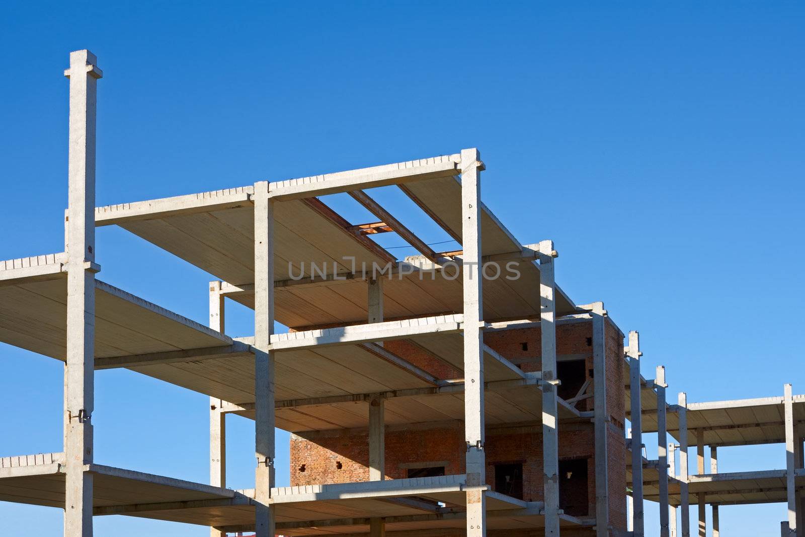 New concrete and bricks building construction on the background of blue sky