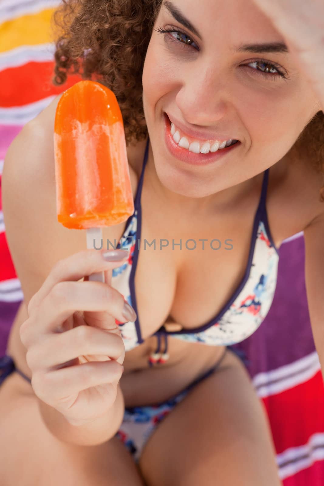 Young smiling and attractive woman holding a delicious ice lolly by Wavebreakmedia