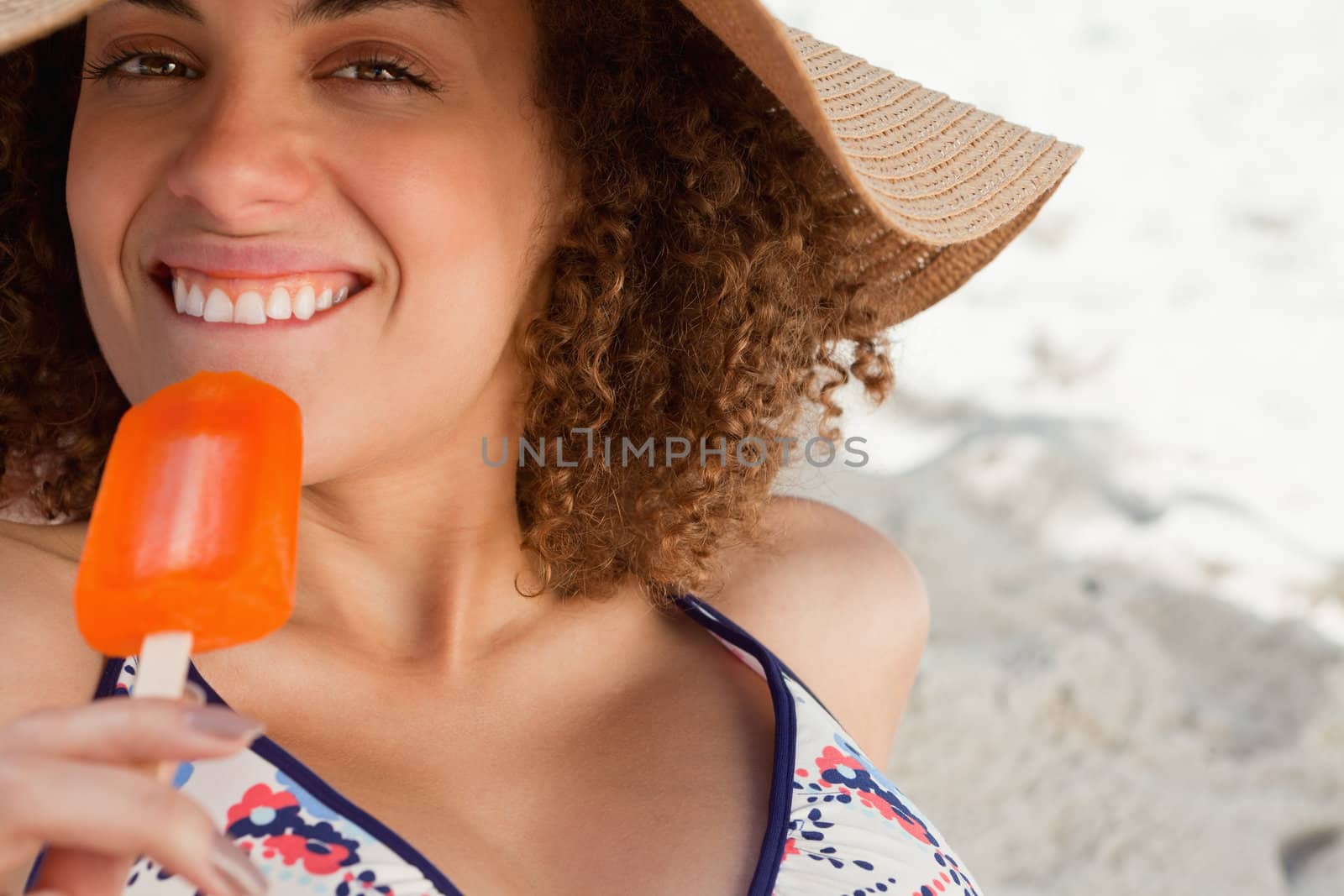 Young attractive woman going to eat an orange ice lolly on the beach by Wavebreakmedia