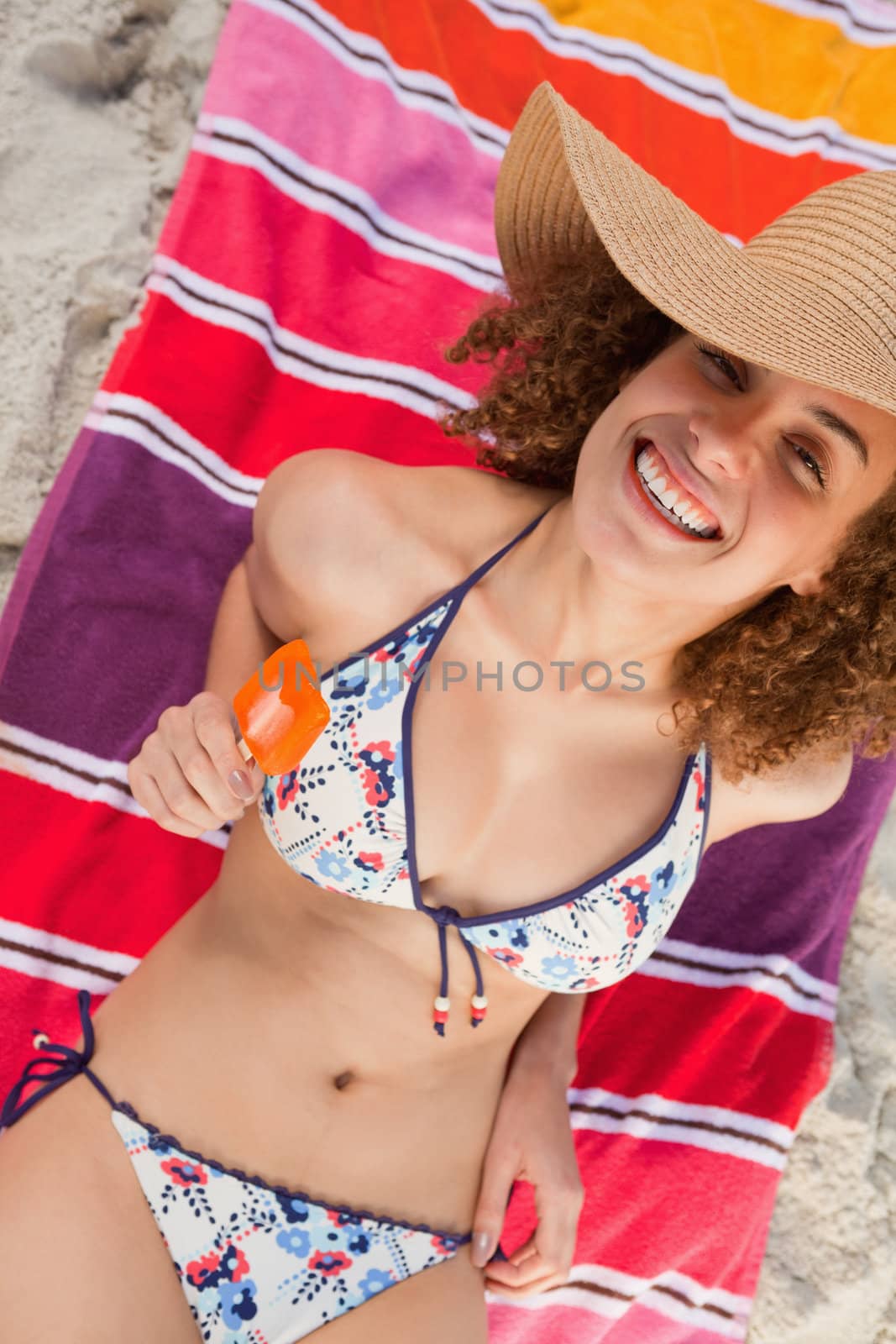 Overhead view of an attractive woman in bikini holding a delicious orange ice cream