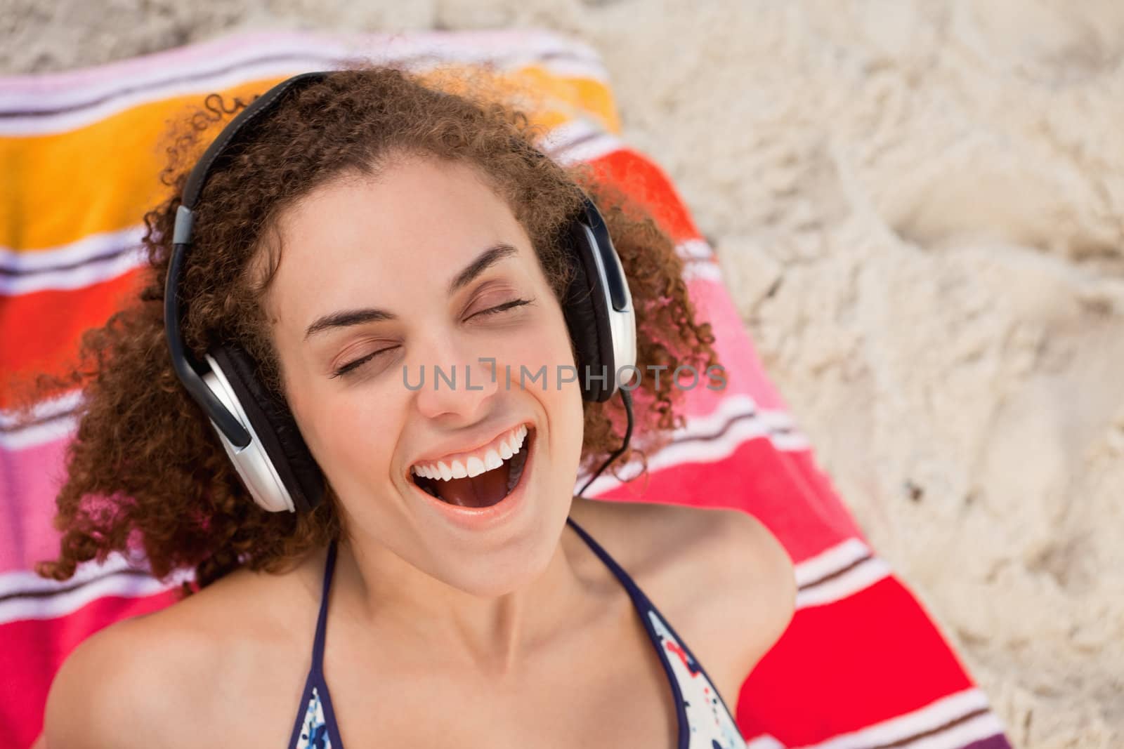 Young woman closing her eyes while listening to music by Wavebreakmedia