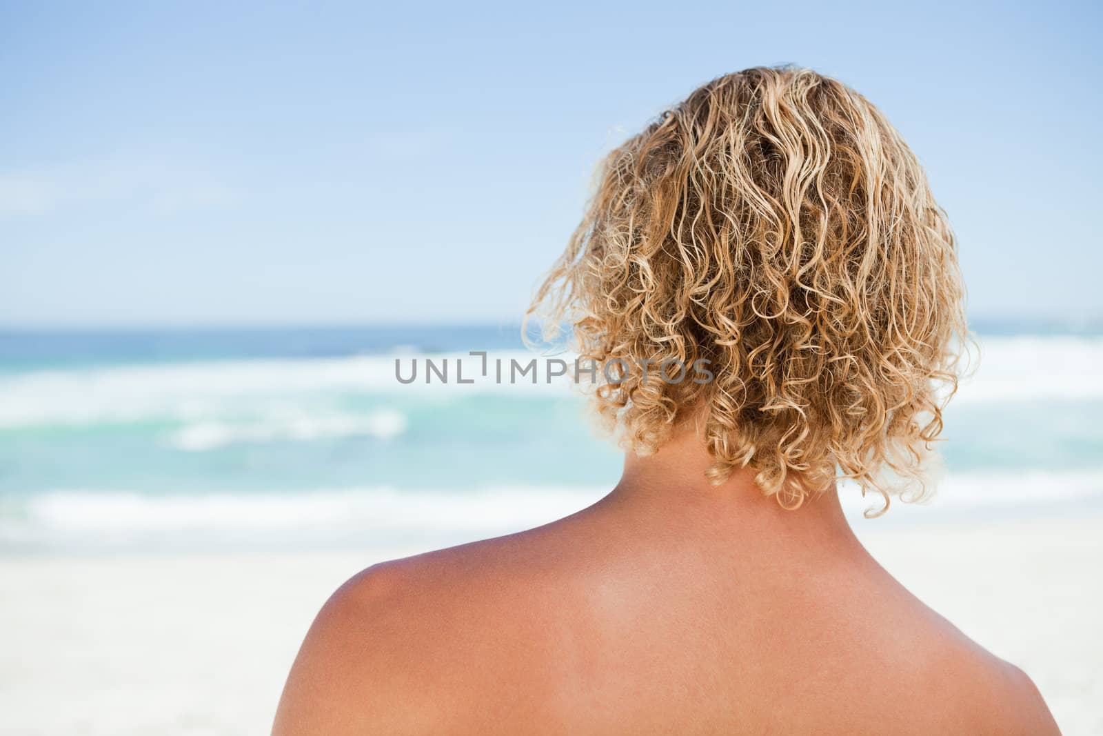 Rear view of a blonde man standing on the beach by Wavebreakmedia