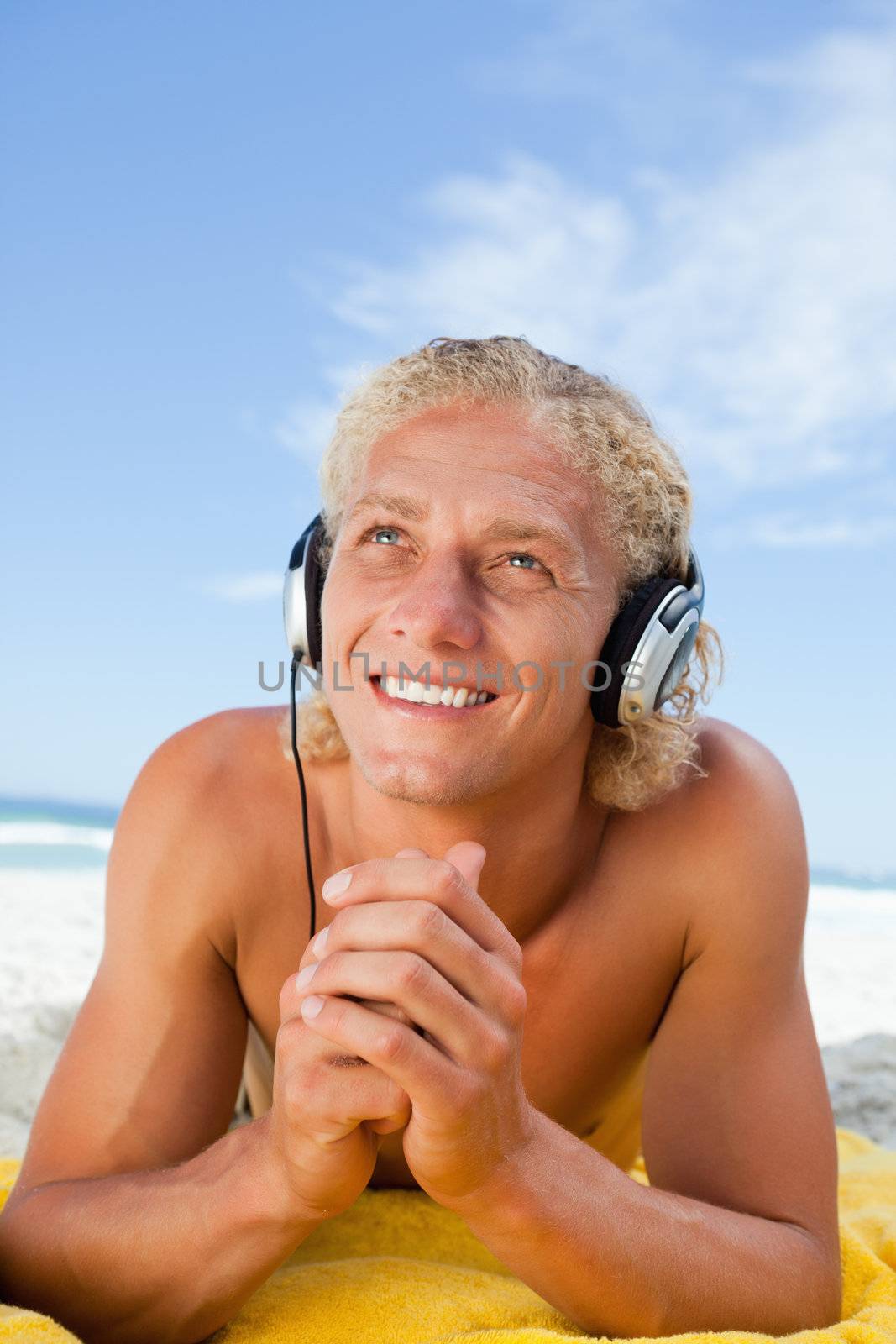 Smiling man crossing his hands while listening to music with his headset