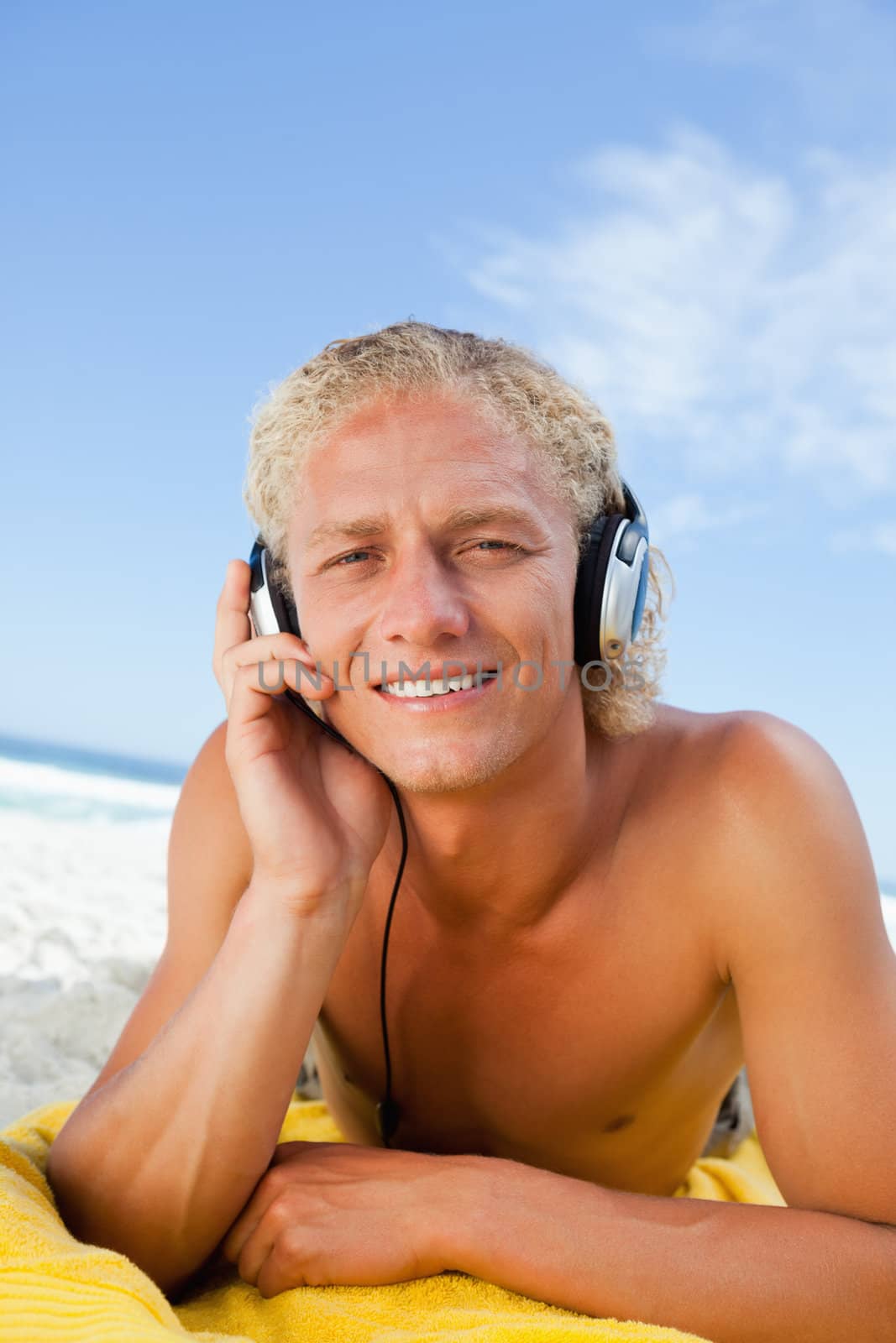 Young blonde man attentively listening to music with his headset by Wavebreakmedia