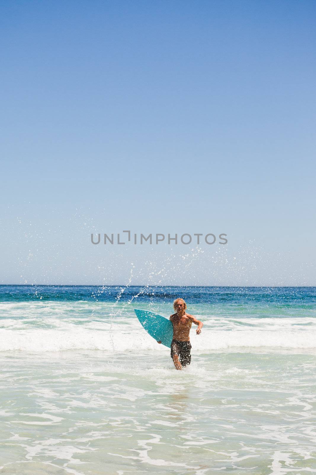 Young blonde man returning to the beach while running by Wavebreakmedia
