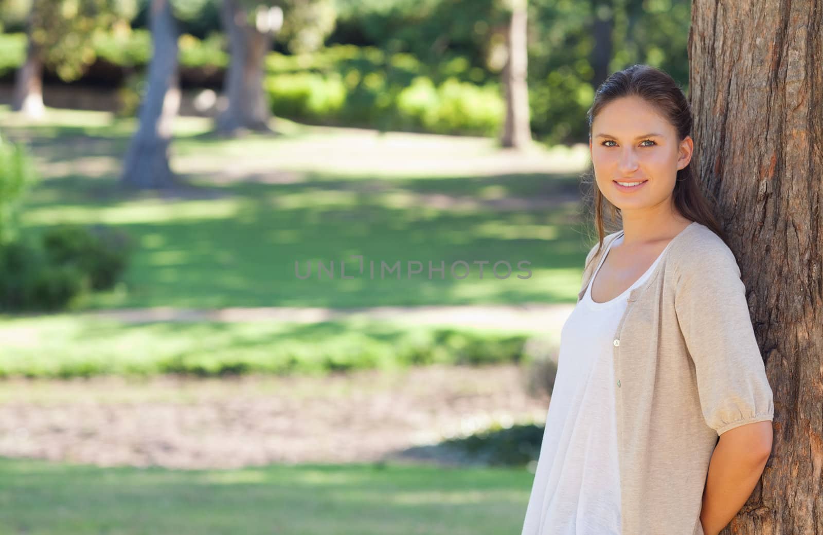 Young woman leaning against a tree