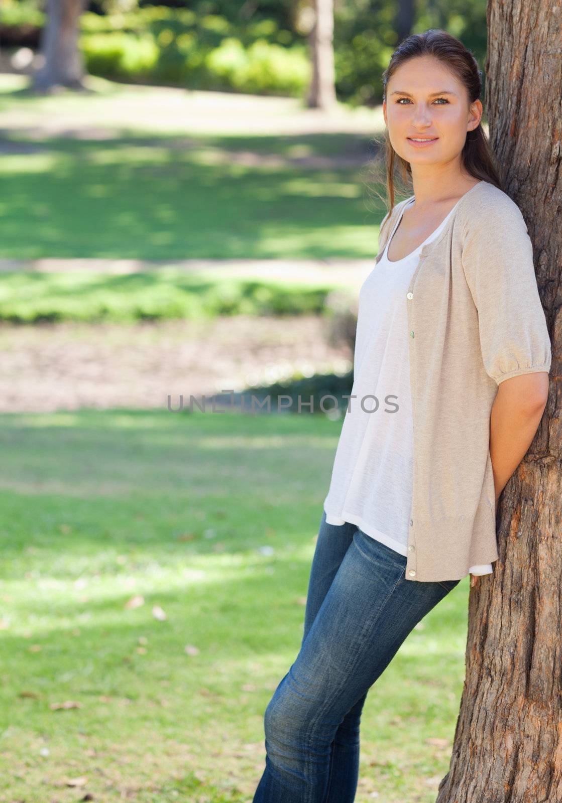 Young woman in the park leaning against a tree