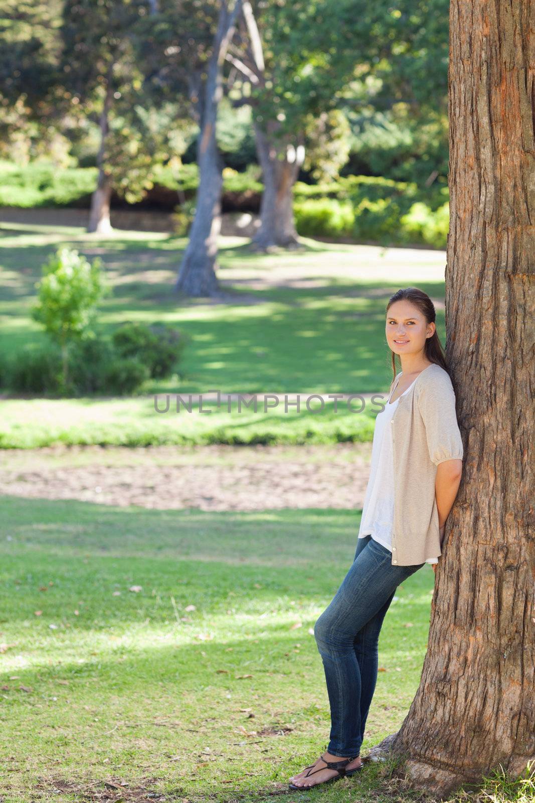 Young woman in the countryside leaning against a tree