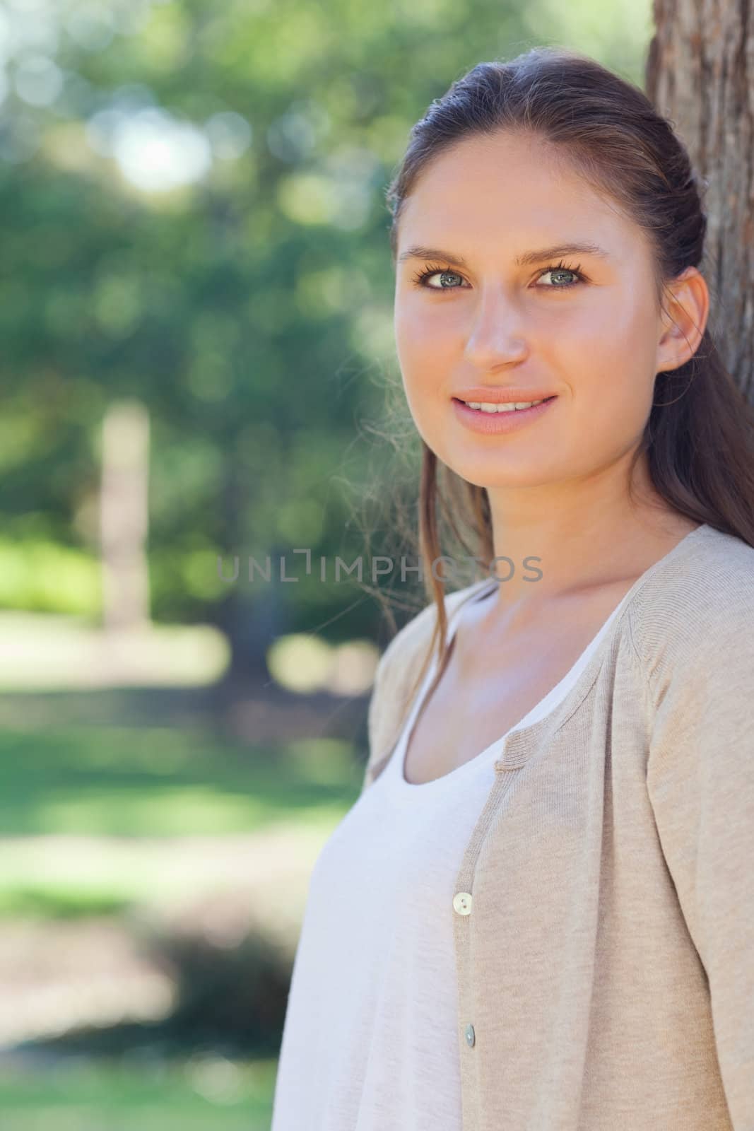 Smiling young woman standing next to a tree