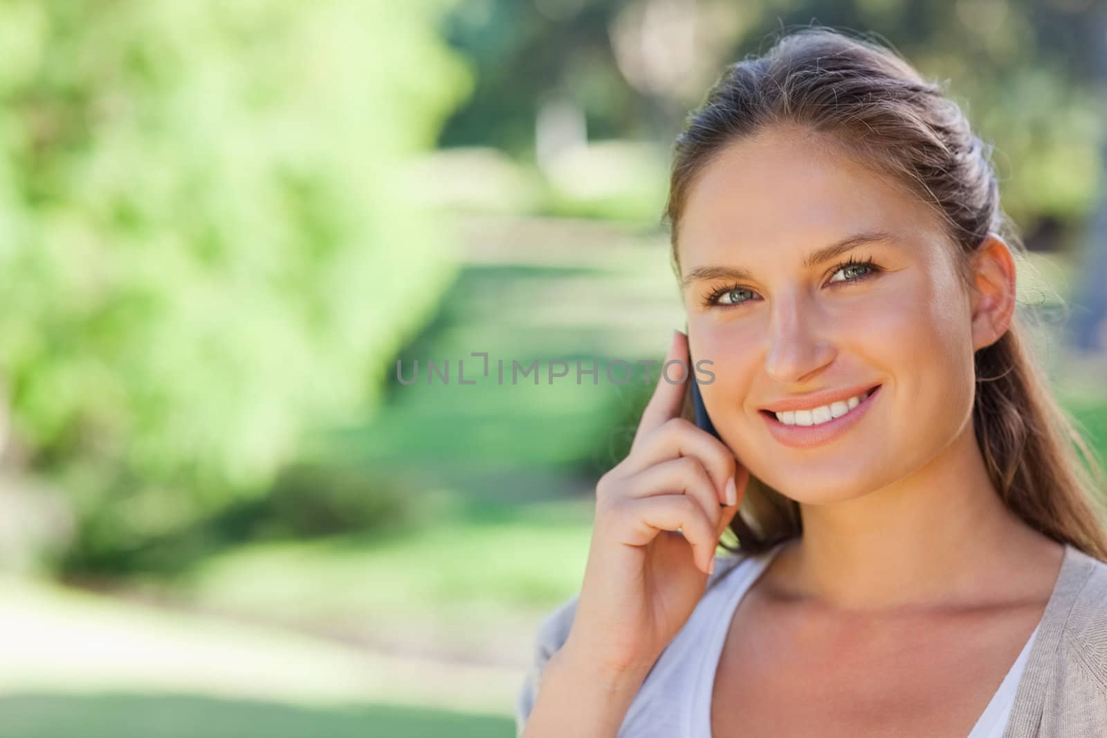 Smiling young woman on her phone in the park